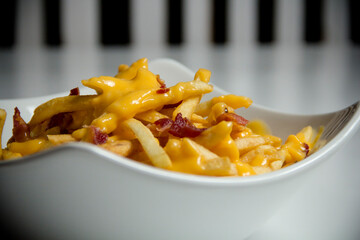 Canadian french fries Poutine with crispy bacon and melted american cheese, close-up.