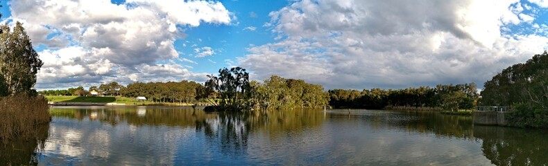 Obraz na płótnie Canvas Beautiful panoramic view of a lake with reflections of blue sky, clouds, and trees on water, lake Pavillion, Sydney Olympic park, Sydney, New South Wales, Australia 