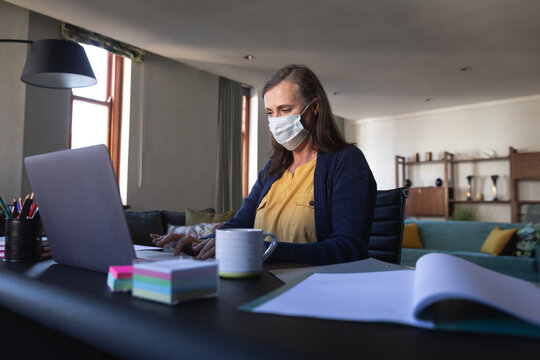 Woman Wearing Face Mask Using Laptop At Home