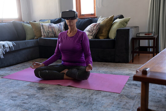 Woman wearing VR headset while performing yoga at home - Powered by Adobe