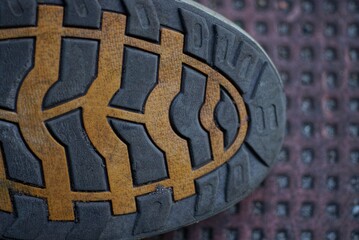 part of the rubber sole of a boot with a brown black pattern lies on a dirty table
