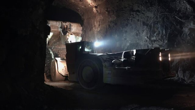 An industrial loader dumps rock and ore in an underground gold mine.