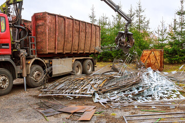 A grapple truck loads scrap industrial metal for recycling.