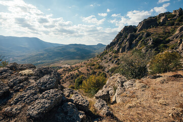 Ridge of brown rocks covered with greenery against a blue sky