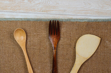 Wooden kitchen appliances spoon fork on a wooden kitchen table with space for text, eco tableware concept