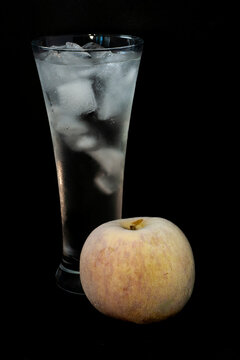 photo of a glass with ice and a frozen apple close-up on a black background