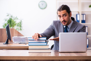 Young male businessman reading books at workplace