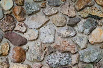 Wall of natural stones with cement between stones. Background with a stone wall