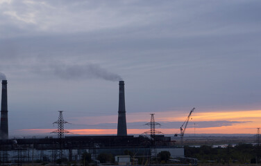 Fototapeta na wymiar Industrial landscape at sunset, pipes and smoke. Smog and environmental problems.