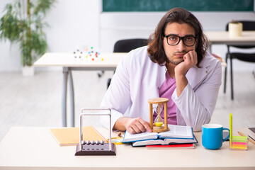 Young male physicist teacher in time management concept