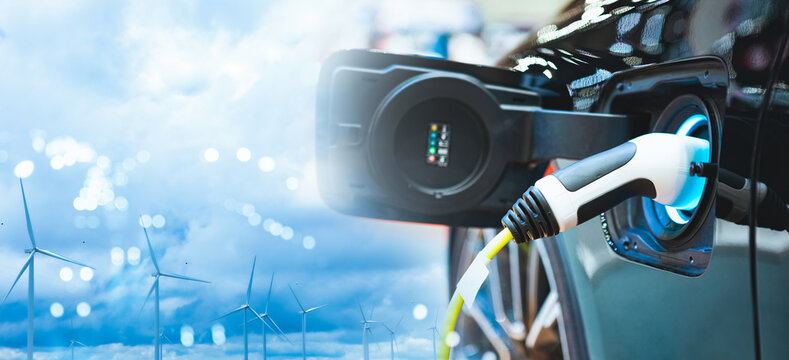 Double exposure of vehicle electric car charge battery with wind turbine and blue sky blur bokeh on panoramic background. Idea nature electric energy to generate electricity. Green energy eco concept.