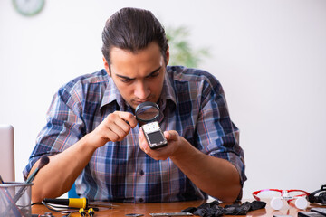 Young male technician repairing mobile phone