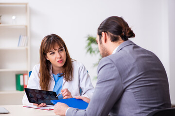 Obraz premium Young female doctor and sick businessman in the office