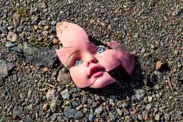 Old broken doll face on ground