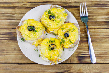 Pieces of baked pork with pineapple, cheese and olive on a wooden table. Top view