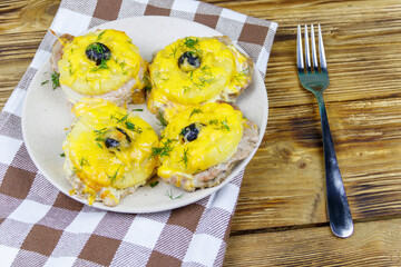 Pieces of baked pork with pineapple, cheese and olive on a wooden table