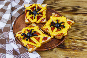 Funny sandwiches with spider and spider web for Halloween party on wooden table