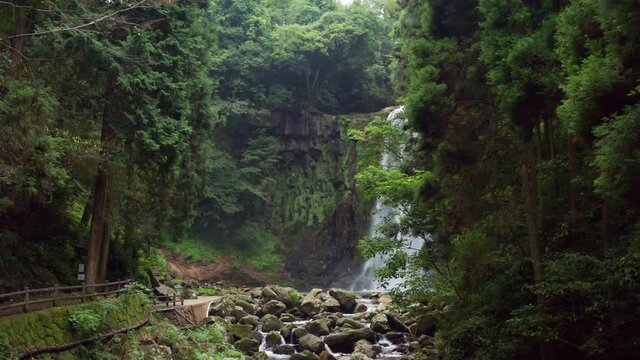 Large waterfall drone reveal through trees Oita Japan sakura falls.