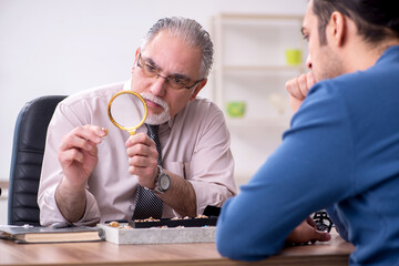 Young man visiting old male jeweler