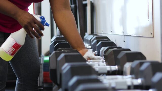 African American Woman Sanitizing Gym Equipment
