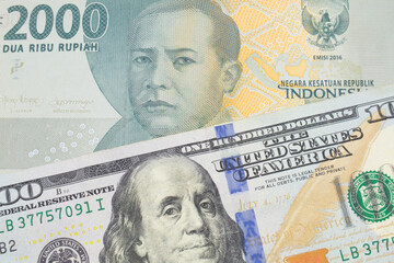 A macro image of a grey two thousand Indonesian rupiah bank note paired up with a blue, one hundred dollar bill from the United States.  Shot close up in macro.