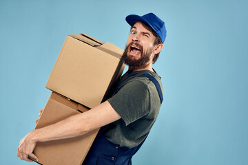 Man in working uniform with boxes in hands delivery service blue background