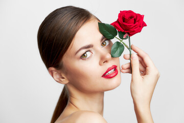 Fototapeta premium Brunette with bare shoulders holding a rose near his face body care 