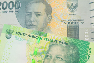 A macro image of a grey two thousand Indonesian rupiah bank note paired up with a shiny, green 10 rand bill from South Africa.  Shot close up in macro.