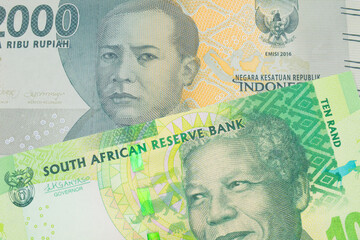 A macro image of a grey two thousand Indonesian rupiah bank note paired up with a shiny, green 10 rand bill from South Africa.  Shot close up in macro.