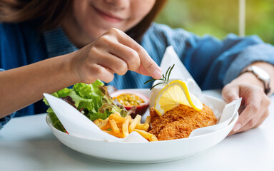 Closeup image of a female chef cooking and decorating a dish of fish and chips