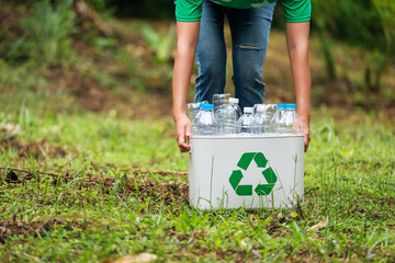 A woman holding a recycle bin with plastic bottles in the outdoors