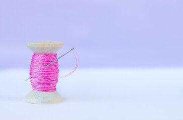 A spool of pink thread and a needle