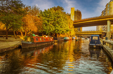 Autumn view of Regent's Canal in London, England at sunset with boats moored on both sides and rising moon in background