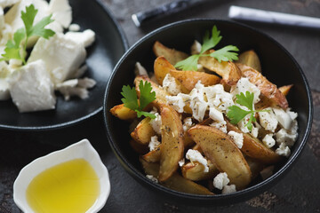 Greek style baked potato wedges with feta cheese and olive oil, closeup, selective focus, studio shot