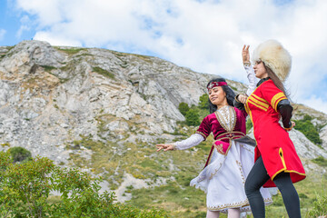 Young girls in national costumes dance a beautiful dance at the foot of the mountain on the ruins of a residential barrack