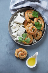 Round grey plate with feta cheese and greek spiral pies made of filo dough, flatlay on a grey concrete background, vertical shot