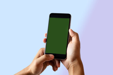 Hand holding green mobile phone with blank white screen.