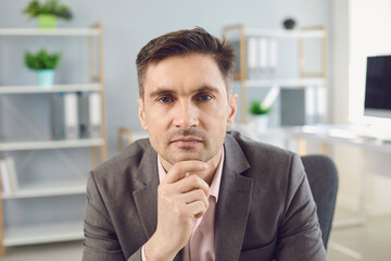 Business man looking at camera during videocall in office