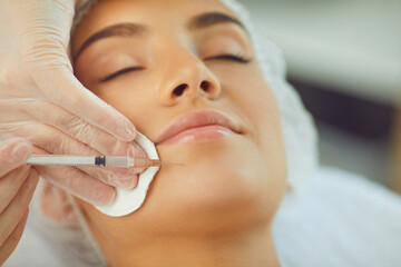 Woman recieving facial beauty botox injection to chin from professional cosmetologist - obrazy, fototapety, plakaty