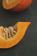 Slice of pumpkin on velvet tablecloth. Autumn harvest, preparation for Halloween or Thanksgiving day. Close up, vertical