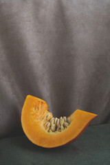 Slice of pumpkin on velvet tablecloth. Minimal composition, retro or vintage style. Copy space, vertical