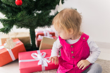 Child holding Christmas gift. Kid having fun at home. Xmas winter holiday concept