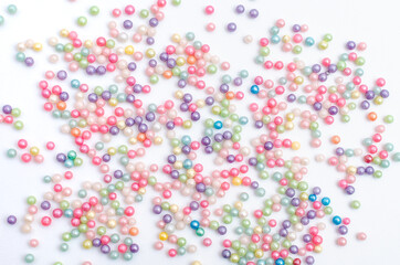 Perlas, chispitas y grageas para decoración de tartas esparcidas sobre fondo blanco.
