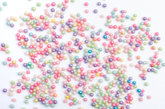 Perlas, chispitas y grageas para decoraci&oacute;n de tartas esparcidas sobre fondo blanco.
