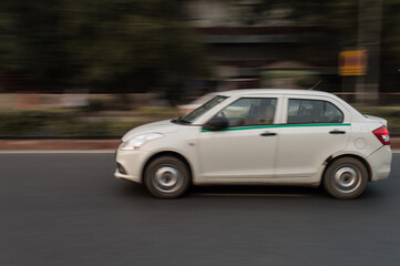 Plakat panning technique of white car which is going somewhere at evening on the road