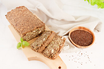 Homemade bread with hazelnut and flax seeds on a wooden Board on light grey marble background 