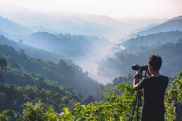 Fototapeta na wymiar cameraman enjoying the nature view of hills and mountain are complex in the morning sunrise, at Mae Wong National park, Kamphaeng Phet, Thailand.