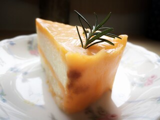 Orange cake is placed on a white plate with a flower pattern.