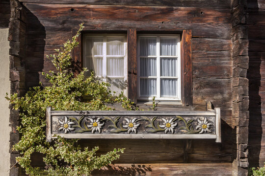Wooden flower pot with edelweiss flower carving placed at the window of old Swiss chalet