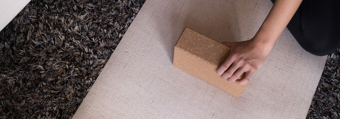 Practising yoga with a block on a beige mat